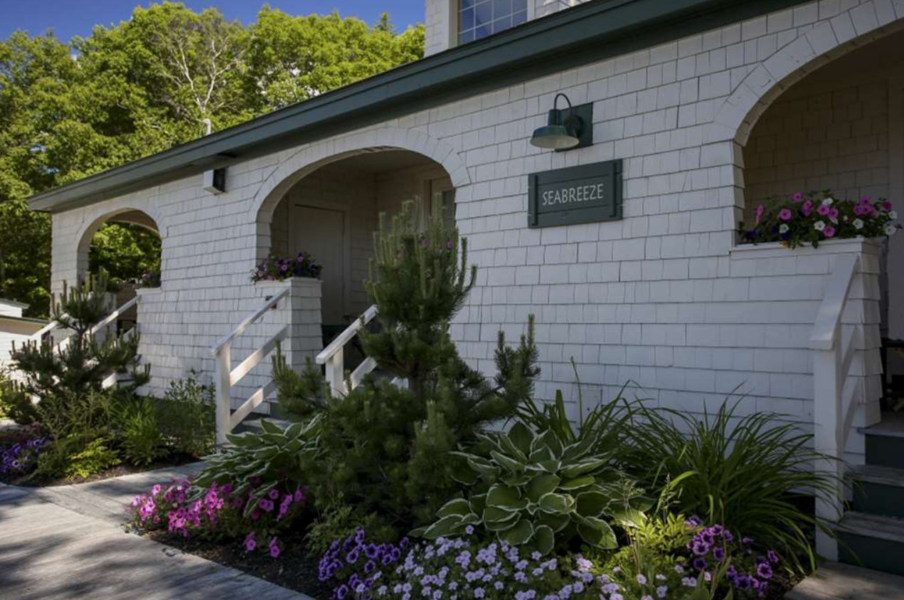 image Lush gardens and storybook arches create a warm welcome at this coastal cottage retreat.