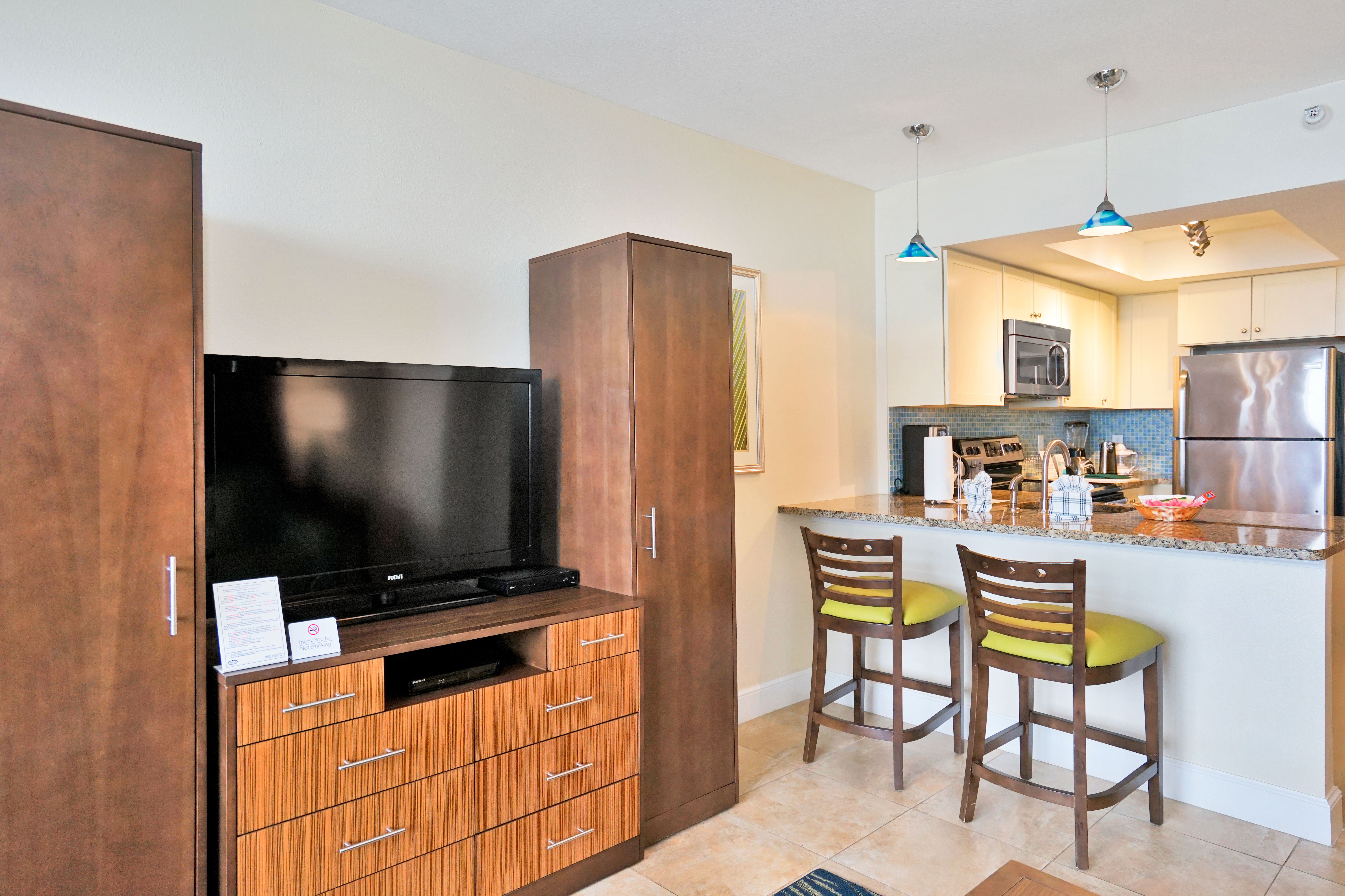 image Living Area/Kitchenette: Cozy living space with a kitchenette, featuring a TV, storage cabinets, and bar stools.