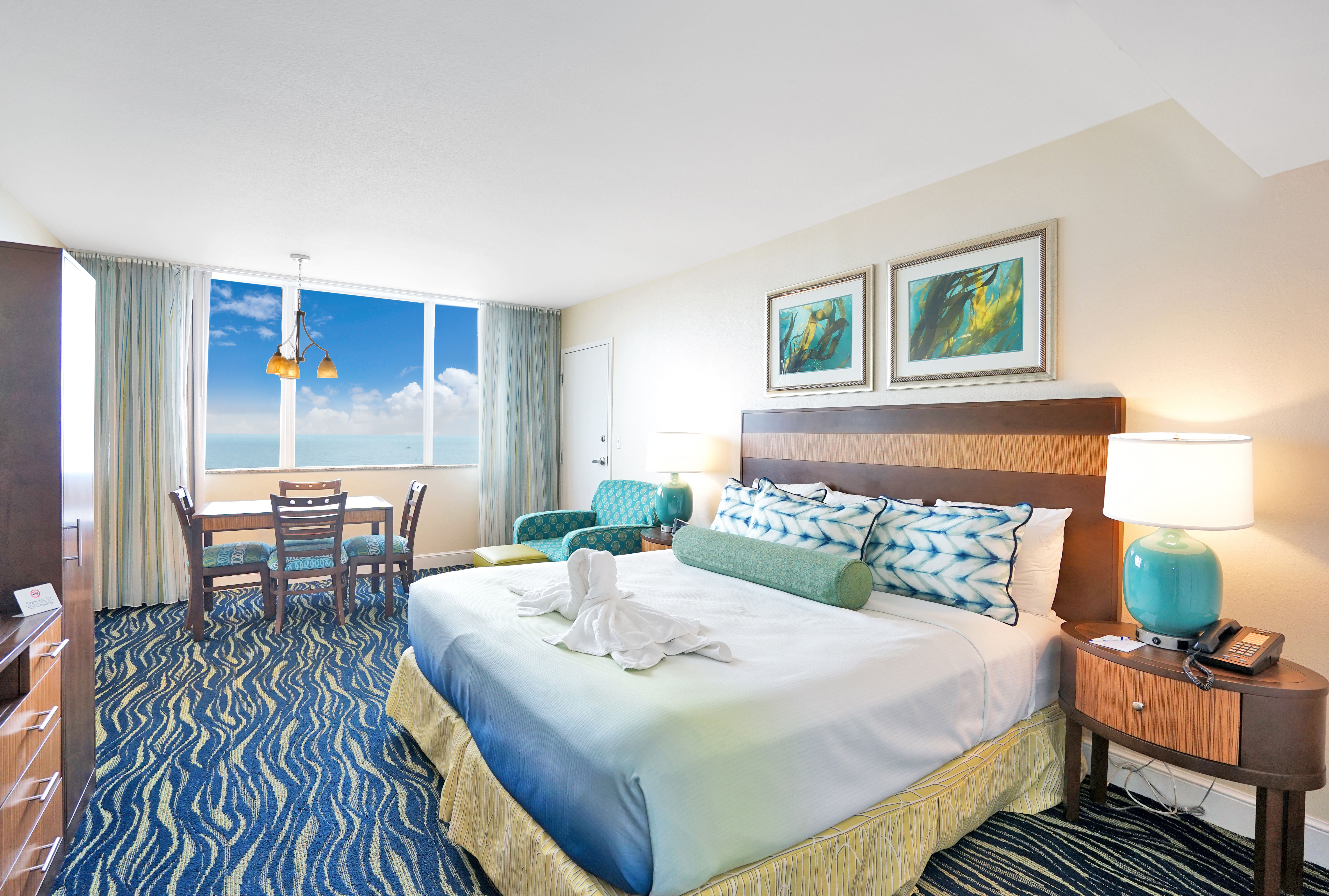image Bedroom Setting: Cozy hotel room with a view of the ocean.