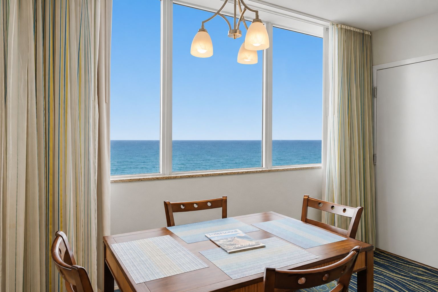 image Ocean view from dining area with table and pendant lighting.
