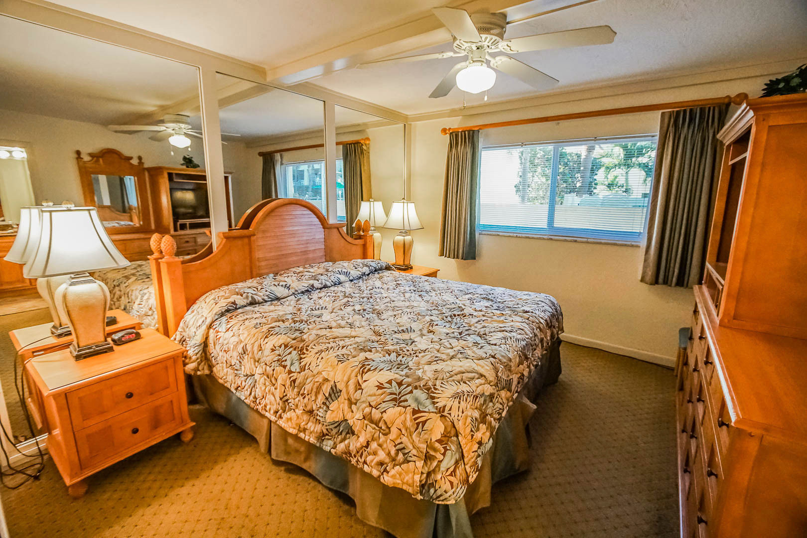 image Relax in the king bedroom suite adorned with a cozy floral comforter and equipped with mirrored furnishings, offering both comfort and elegance for a restful night.