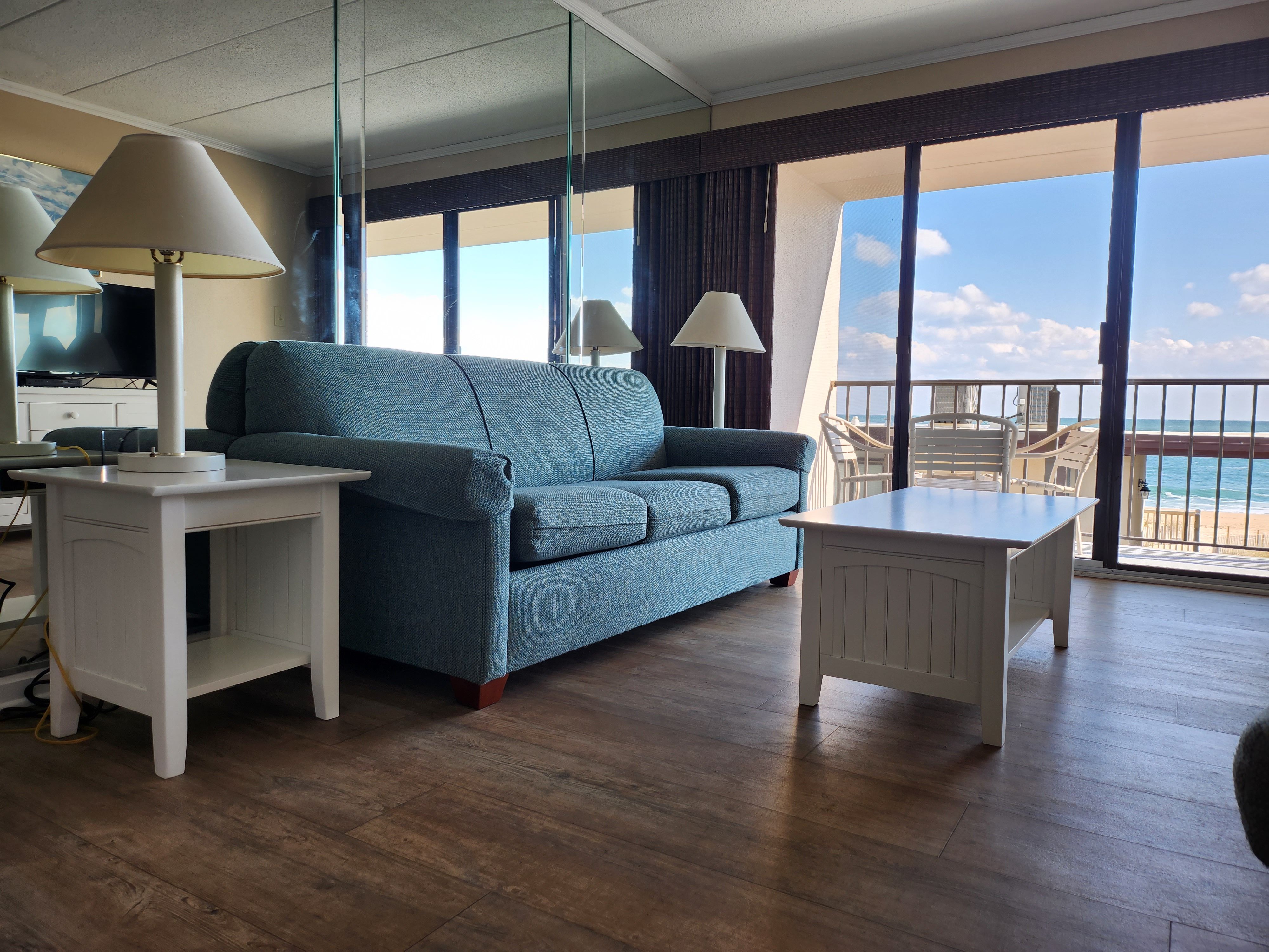 image Enjoy a spacious living room with a smart TV and expansive ocean views from the windows, ideal for unwinding after a day of beach activities.