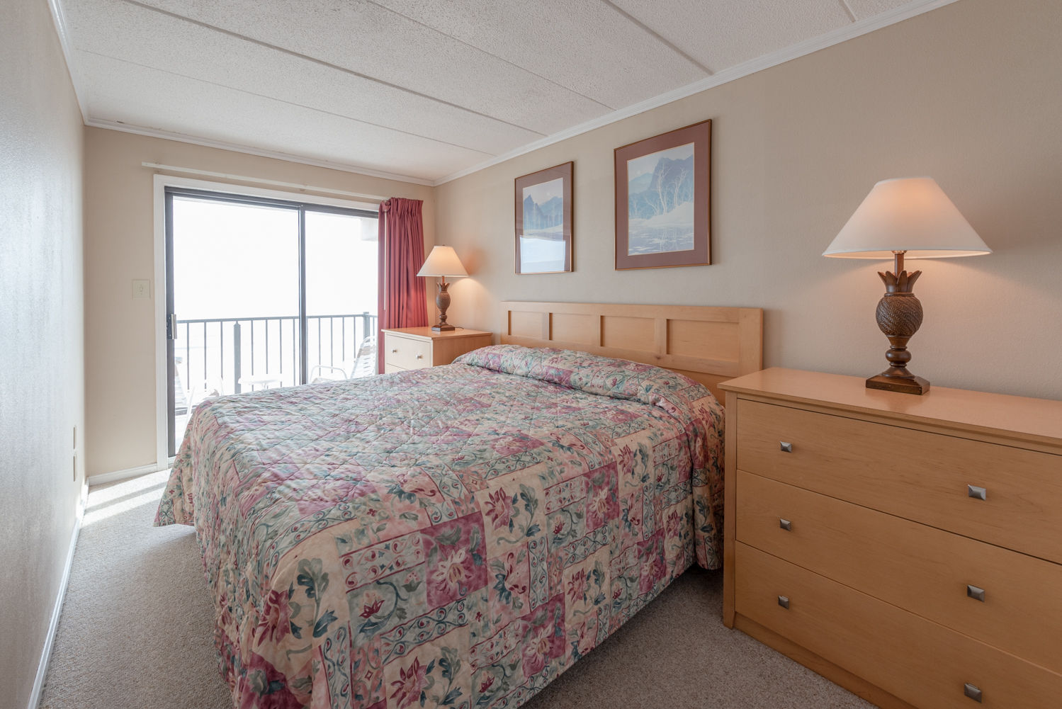image Relax in this cozy bedroom featuring a comfortable bed and direct access to a private balcony with stunning oceanfront views.