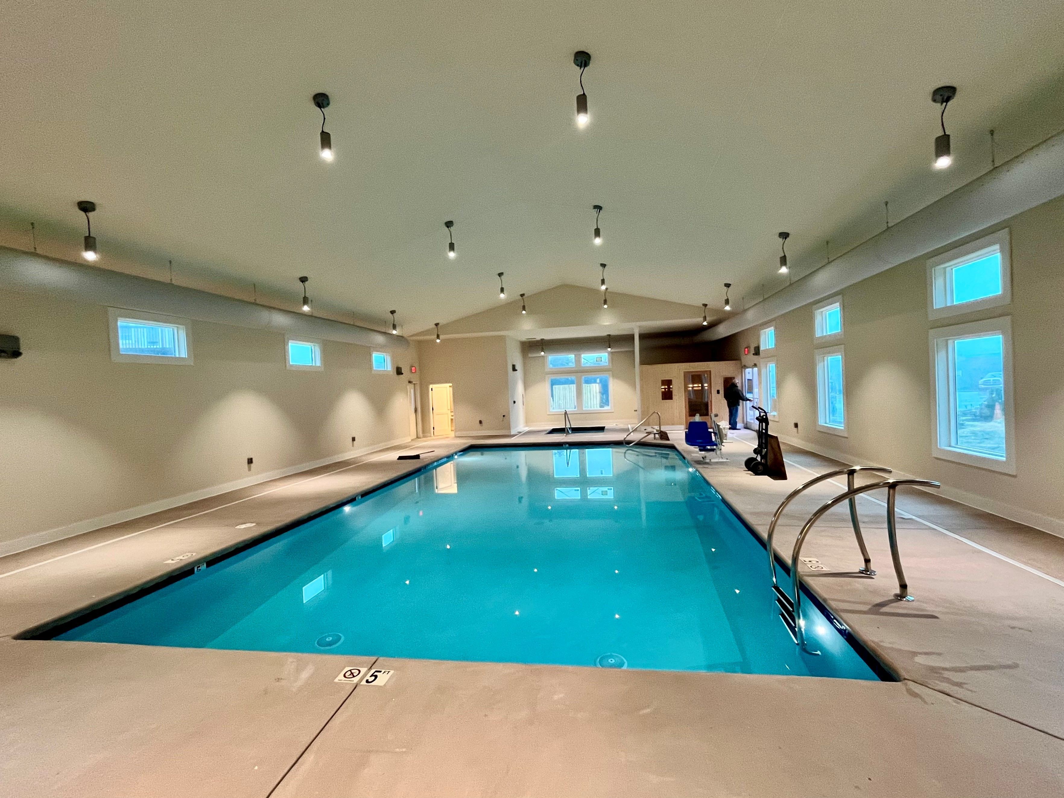 image An indoor swimming pool area with clear blue water, large windows letting in natural light, and a minimalist design.