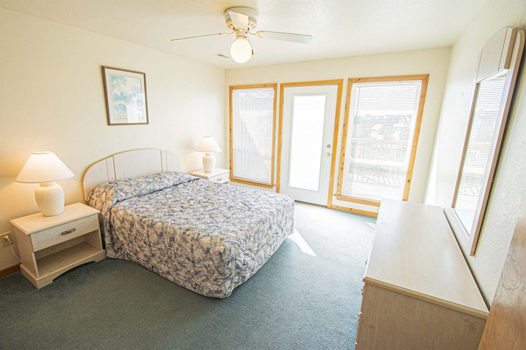 image A bright and inviting bedroom with floral bedding, natural light from large windows, and a relaxed, airy design.