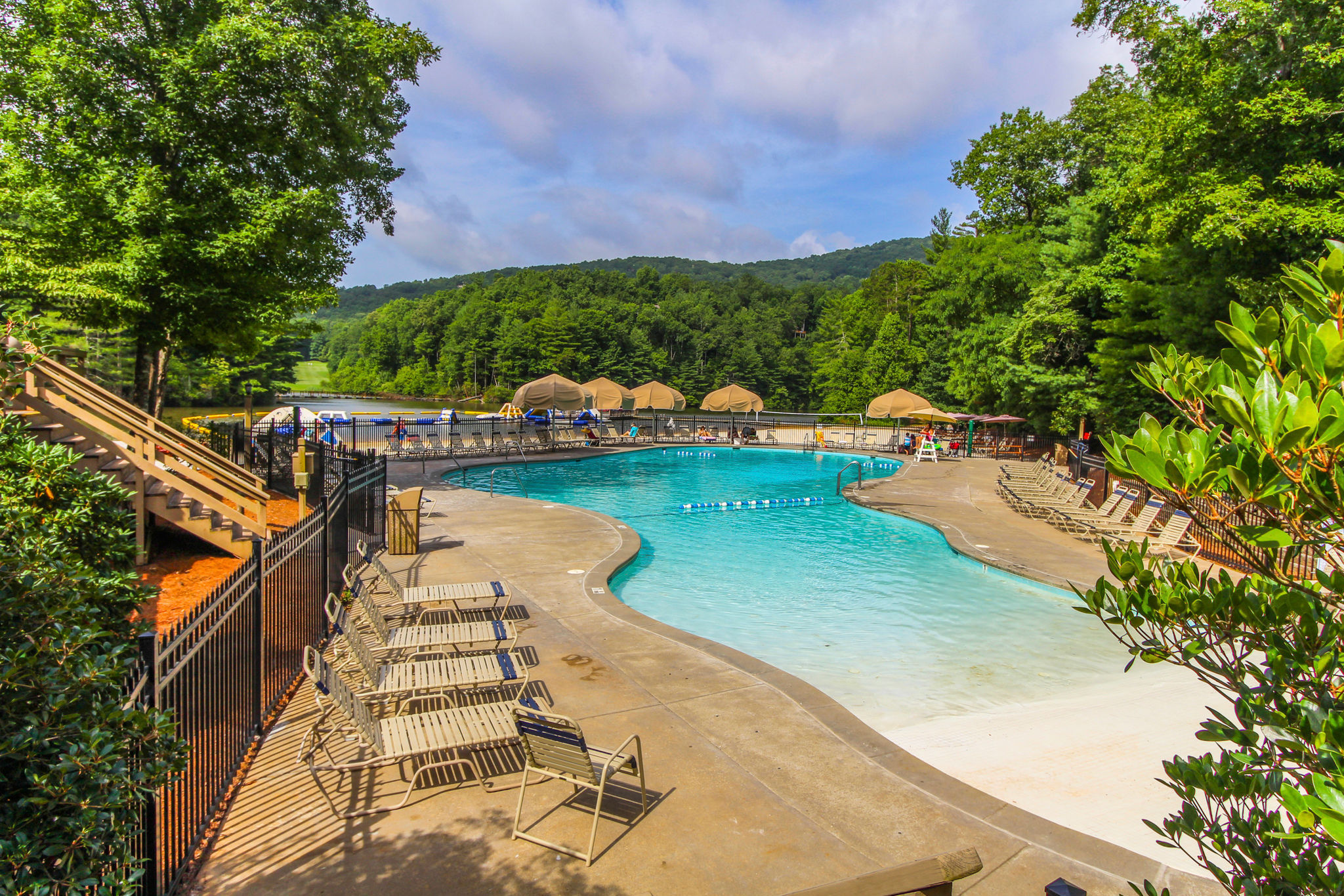 image Dive into relaxation at the sparkling pool surrounded by lush greenery, featuring lounge chairs for soaking up the sun on warm days.