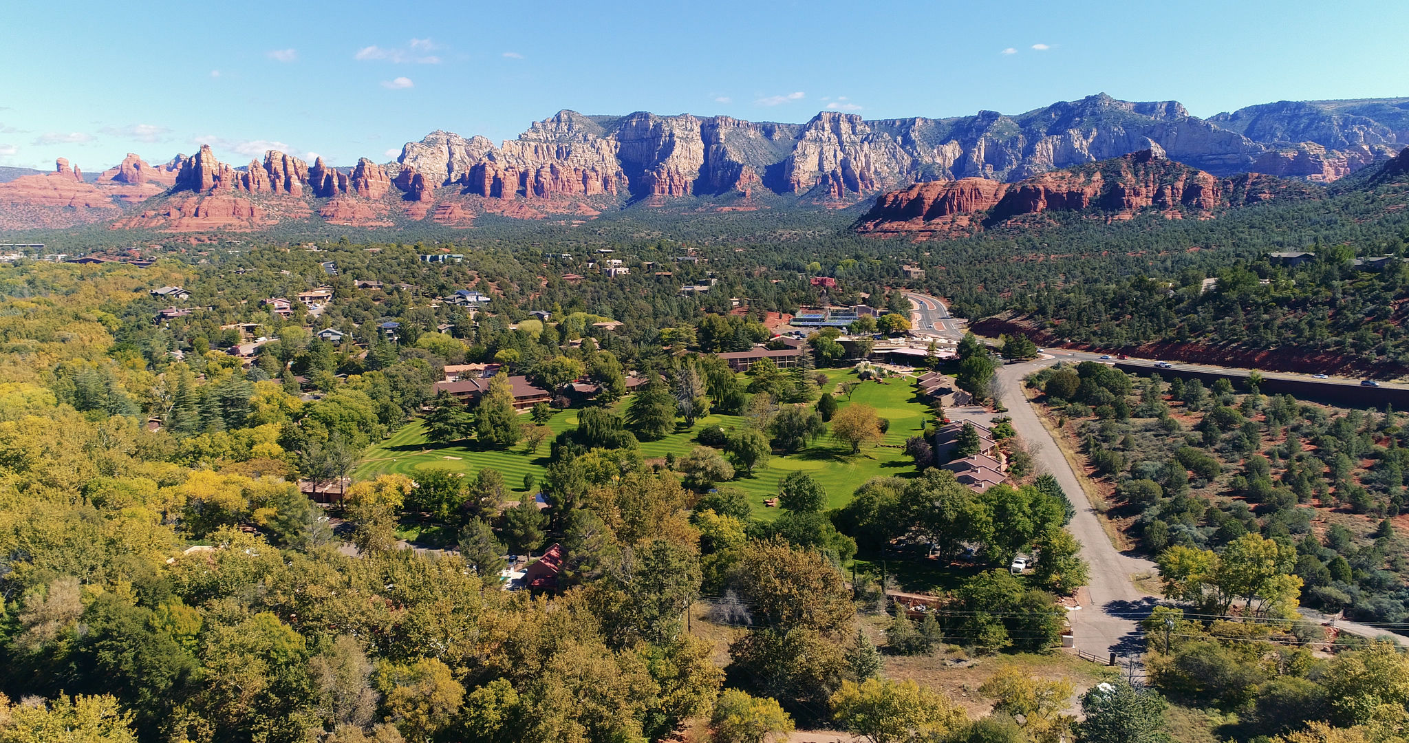 image A stunning aerial view of Sedona's vibrant landscape, showcasing lush greenery against the backdrop of striking red rock formations, perfect for serene retreats.