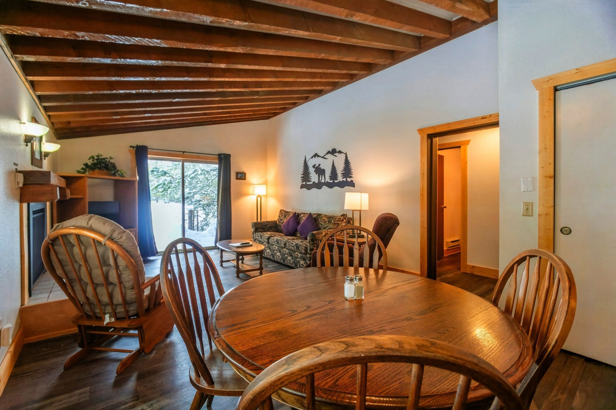 image Relax in the inviting living space featuring a wood-burning fireplace and easy access to a beautiful balcony overlooking the forest.