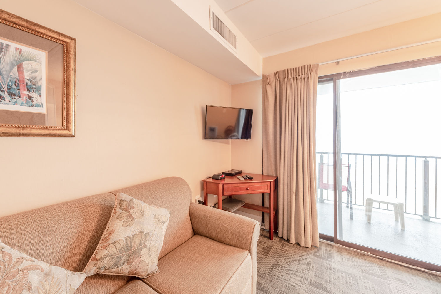 image Enjoy serene oceanfront views from the living area, complete with a TV and direct access to the balcony.