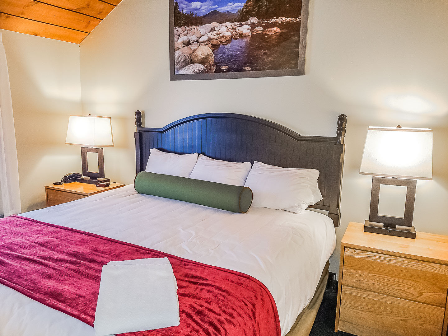image Cozy and inviting, this bedroom features a plush king bed with elegant bedding, two bedside lamps, and a scenic mountain view, perfect for restful nights at the Village of Loon Mountain Resort.