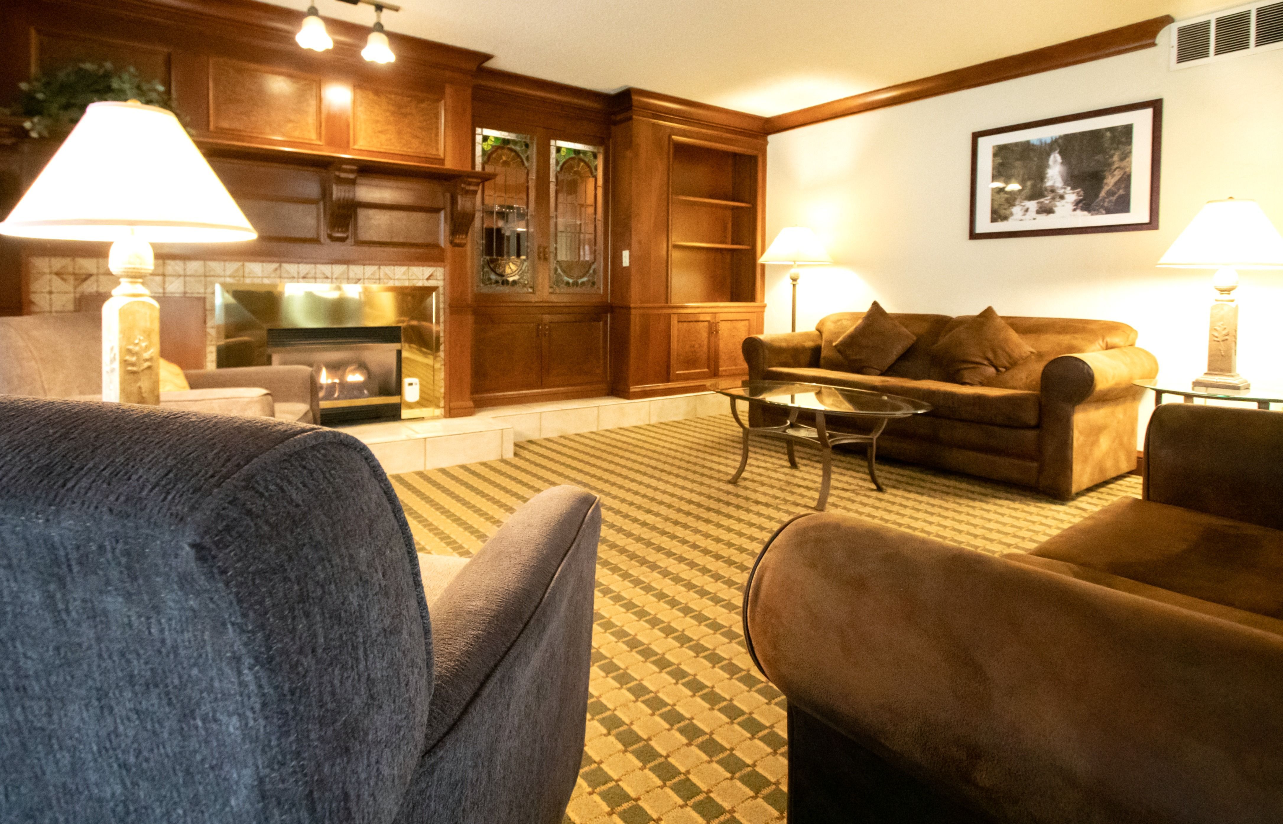 image Cozy living room featuring a warm fireplace, elegant wooden decor, and ample seating for relaxation.