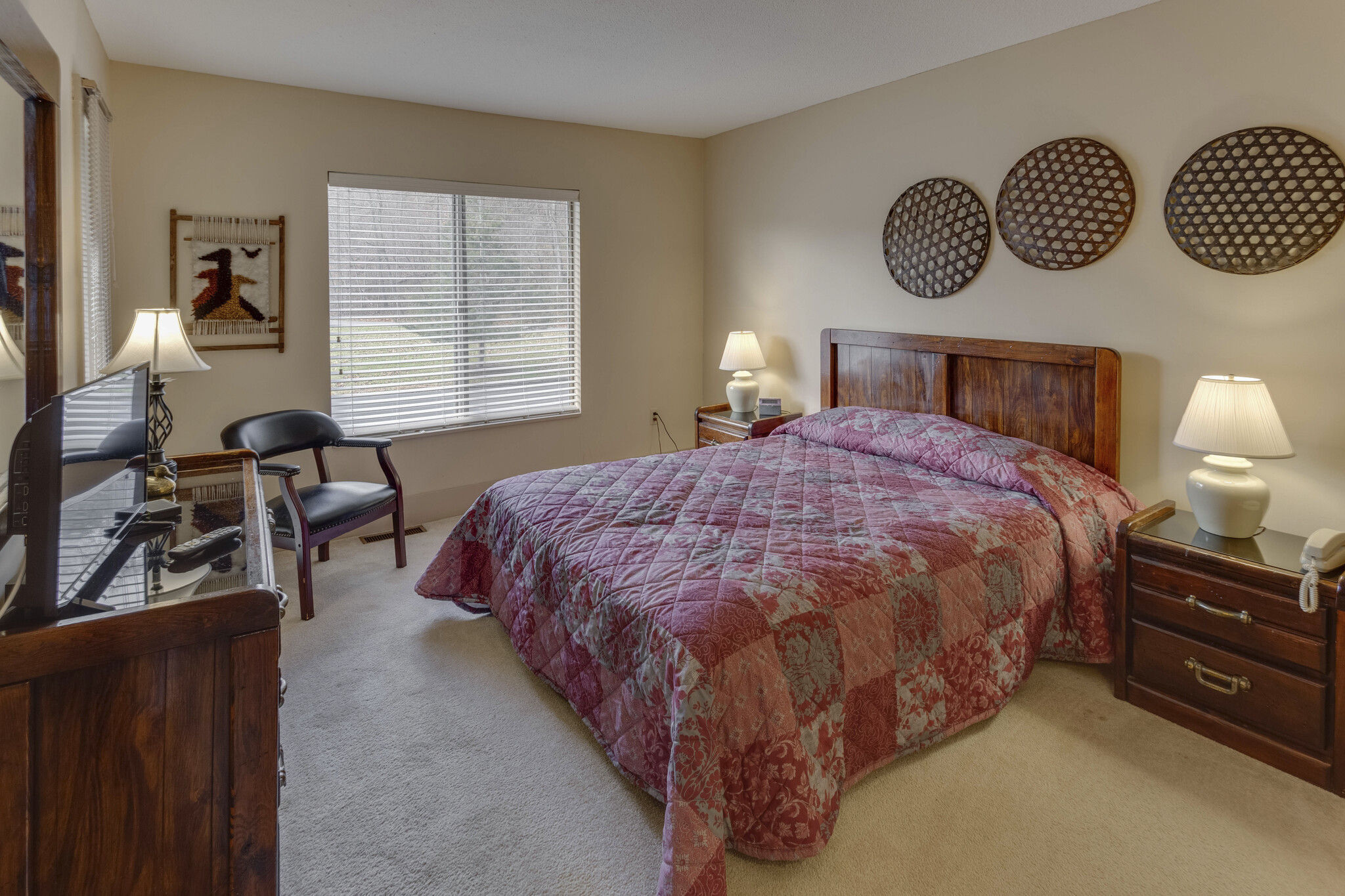 image Retreat to the inviting bedroom, featuring a plush bed, smart TV, and large windows for natural light, while having easy access to in-suite washer/dryer facilities.