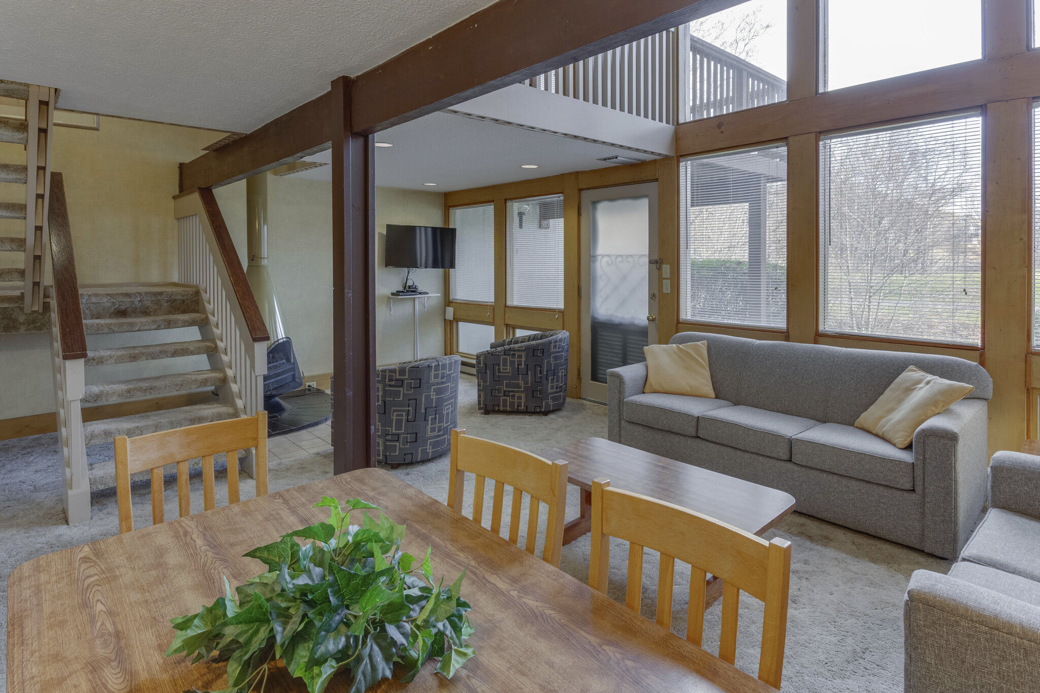 image Embrace cozy mountain living in this spacious common area, complete with a fireplace and surrounded by large windows offering serene creekside views.