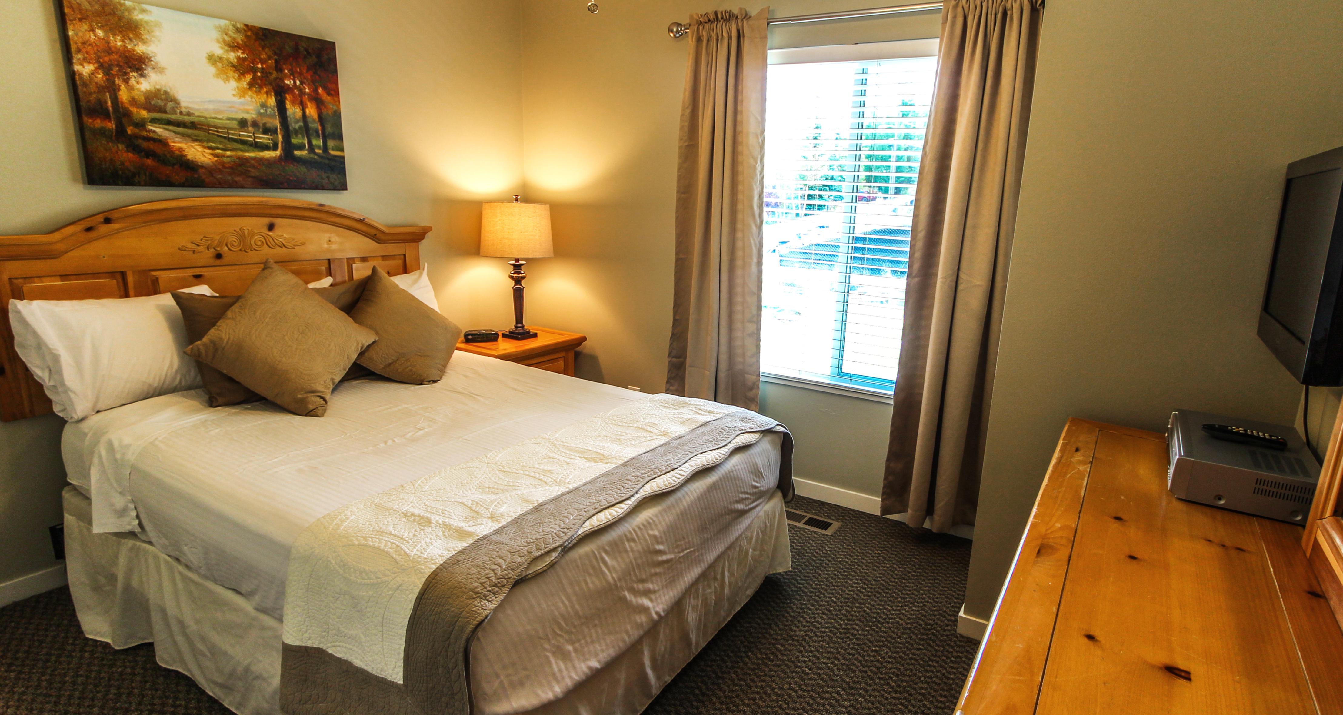 image Relax in this elegantly designed queen bedroom that features a warm ambiance, perfect for unwinding after a day filled with mountain activities, complete with a flat-screen TV for your entertainment.