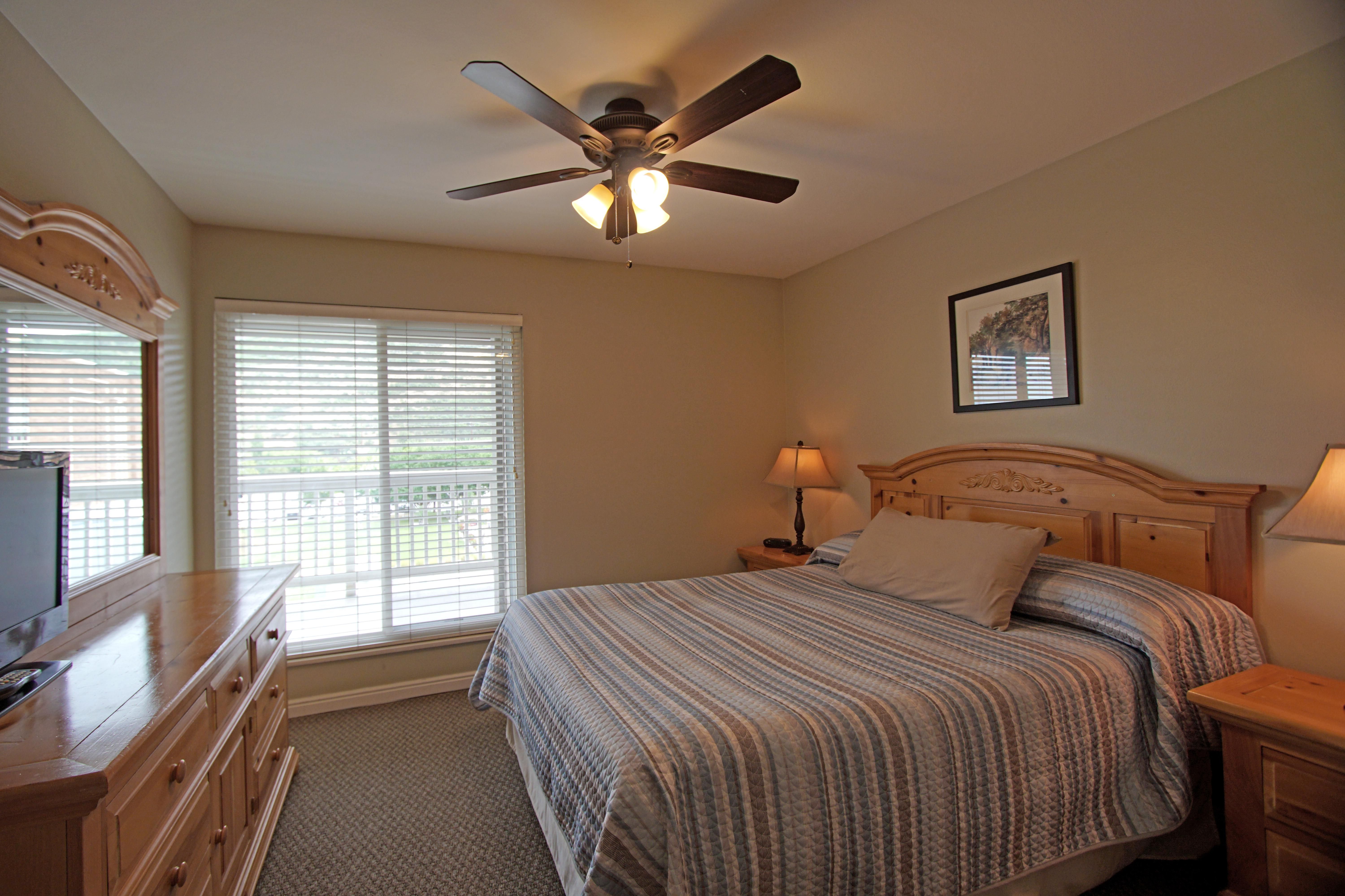 image Relax in this cozy queen bedroom featuring natural light, a stylish ceiling fan, and convenient storage, ideal for a restful night's sleep after skiing.