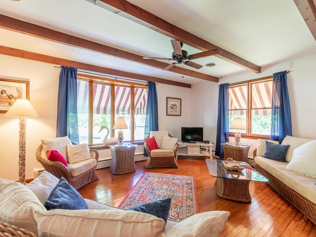 image Relax in this cozy living room featuring warm wood beams, plenty of natural light, and a comfortable atmosphere ideal for family gatherings or quiet evenings by the fireplace.