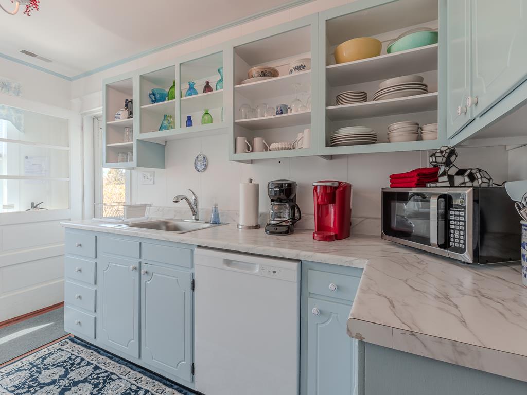 image This charming blue-painted kitchen features antique decor and seamless access to the outdoor ambiance, making it the perfect space for culinary creativity and entertaining with a touch of coastal charm.