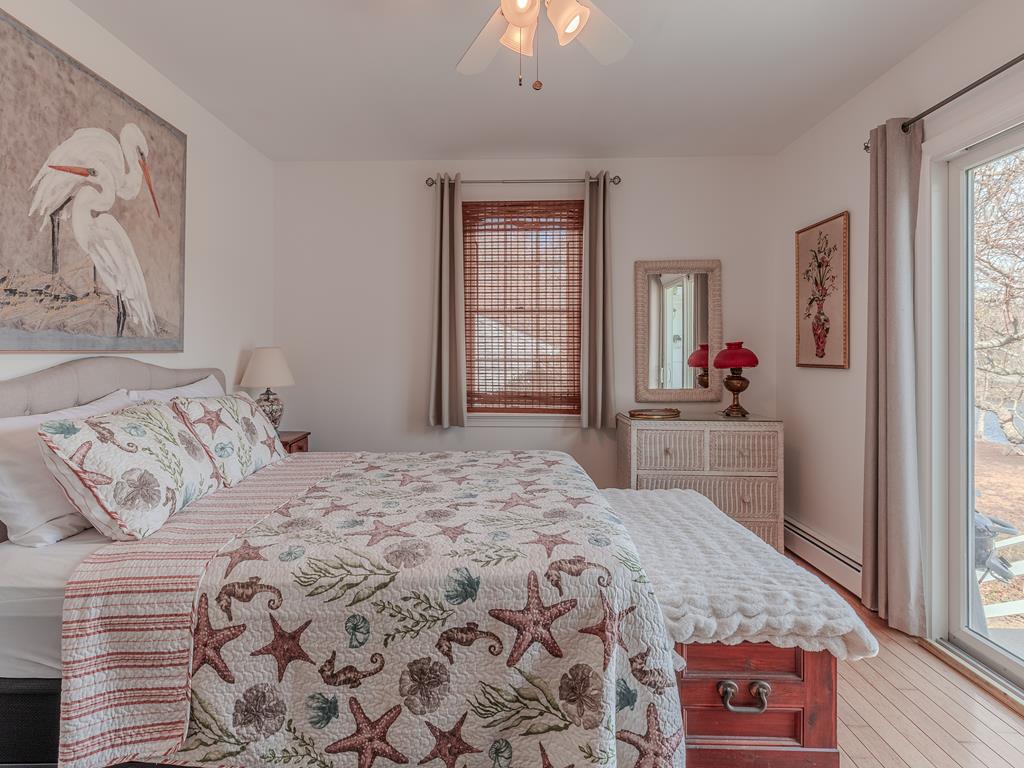 image Enjoy a restful night's sleep in this beautifully decorated bedroom, where coastal themes meet modern comforts and provide direct access to the picturesque outdoors.