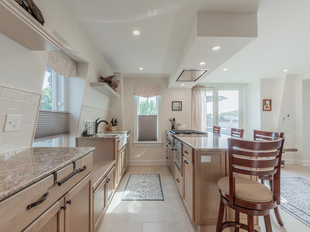 image This beautifully designed kitchen allows for seamless entertaining, boasting granite countertops, ample natural light, and elegant shelving for a touch of charm.