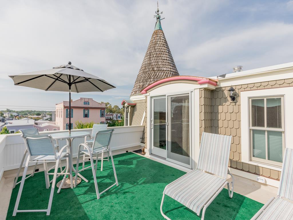 image The private rooftop deck offers breathtaking views, perfect for relaxing under the sun with a refreshing beverage amidst the coastal breeze.