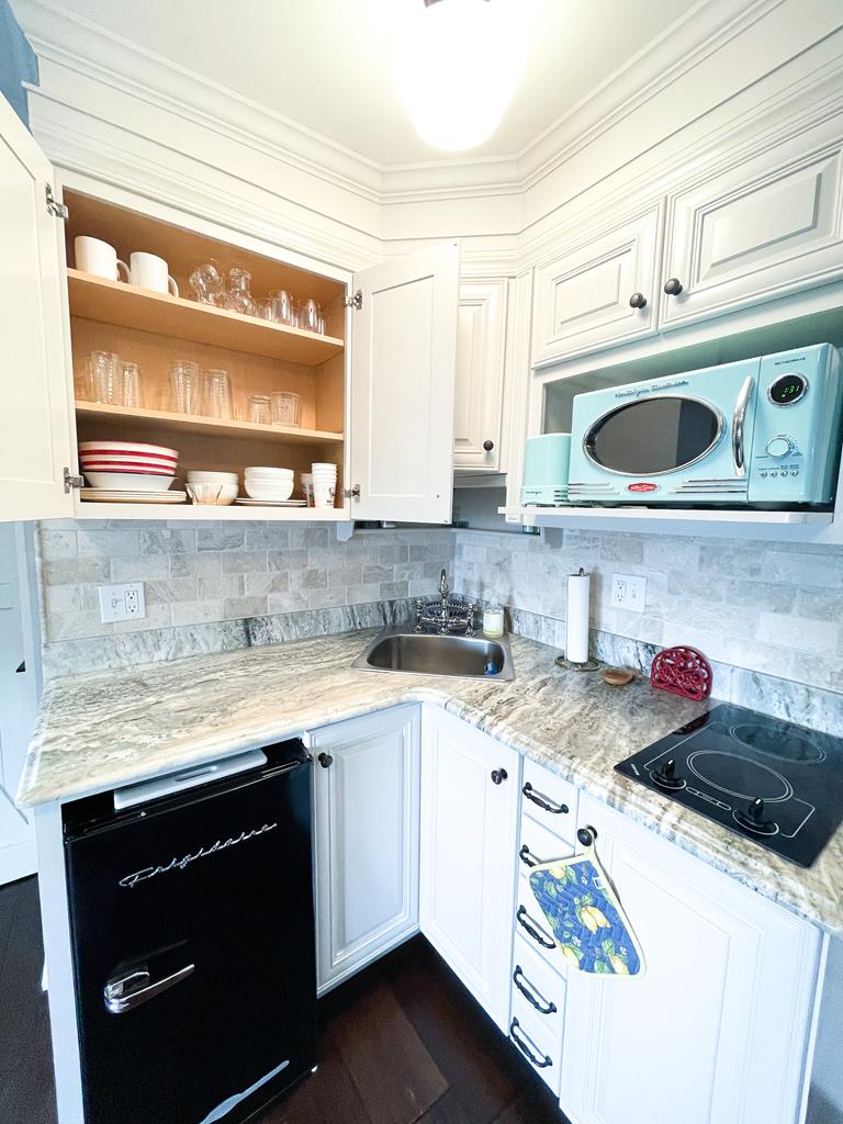 image Enjoy cooking in this charming kitchenette featuring quartz countertops, modern appliances, and stylish cabinetry, perfect for your beach block getaway.