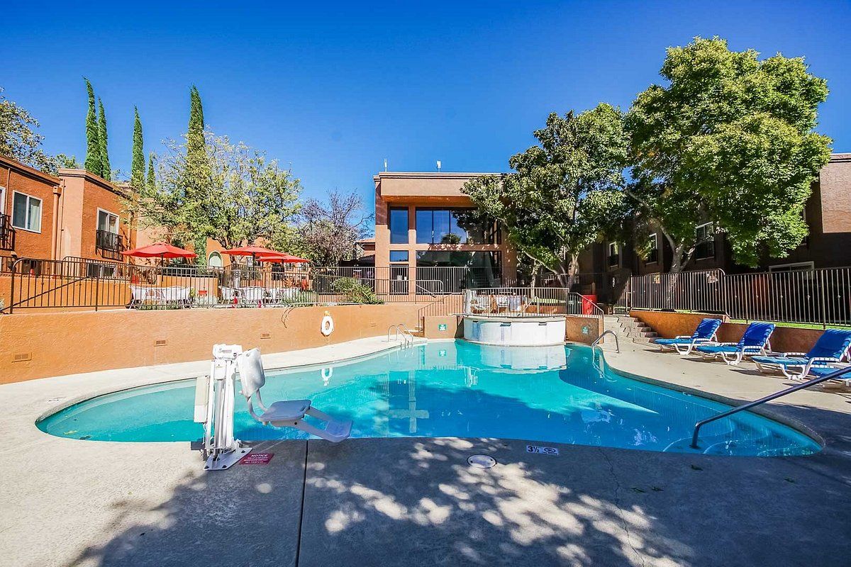 image Enjoy the sunny outdoor pool area complete with a hot tub and inviting lounge chairs, perfect for soaking up the sun.