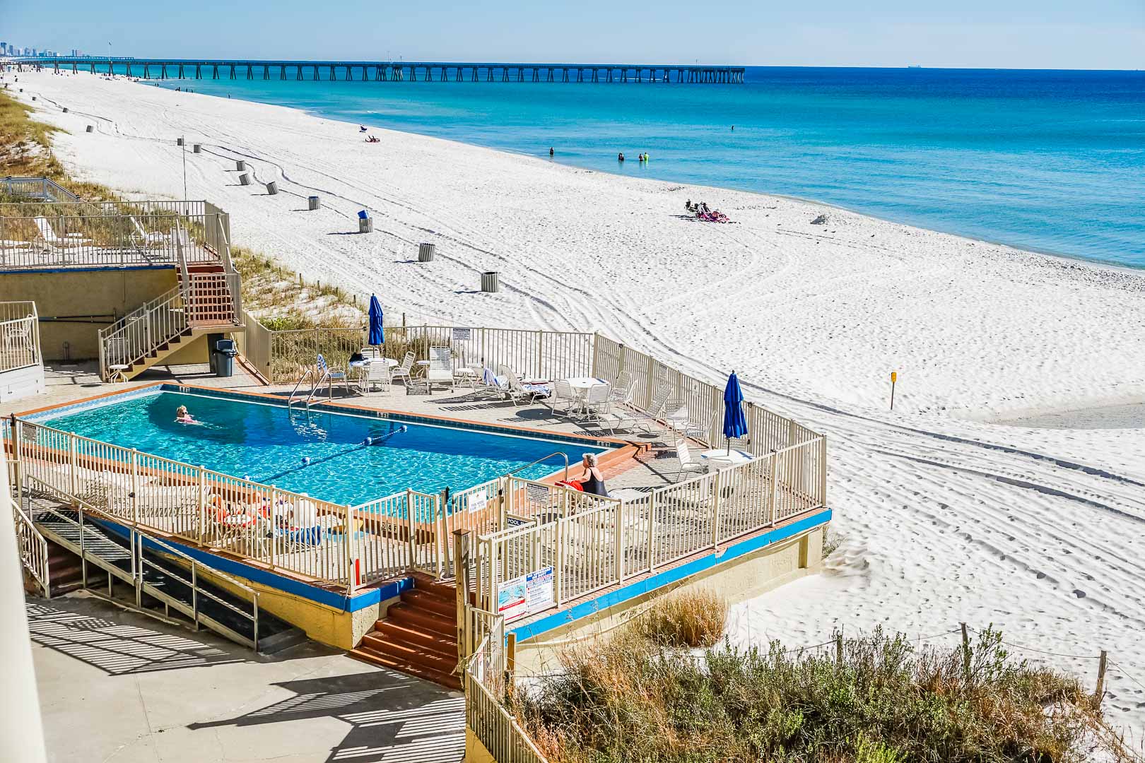image The beachfront studio offers a stunning view of the white sand beach and the sparkling turquoise waters of Panama City Beach, complete with a refreshing swimming pool surrounded by loungers for relaxation.