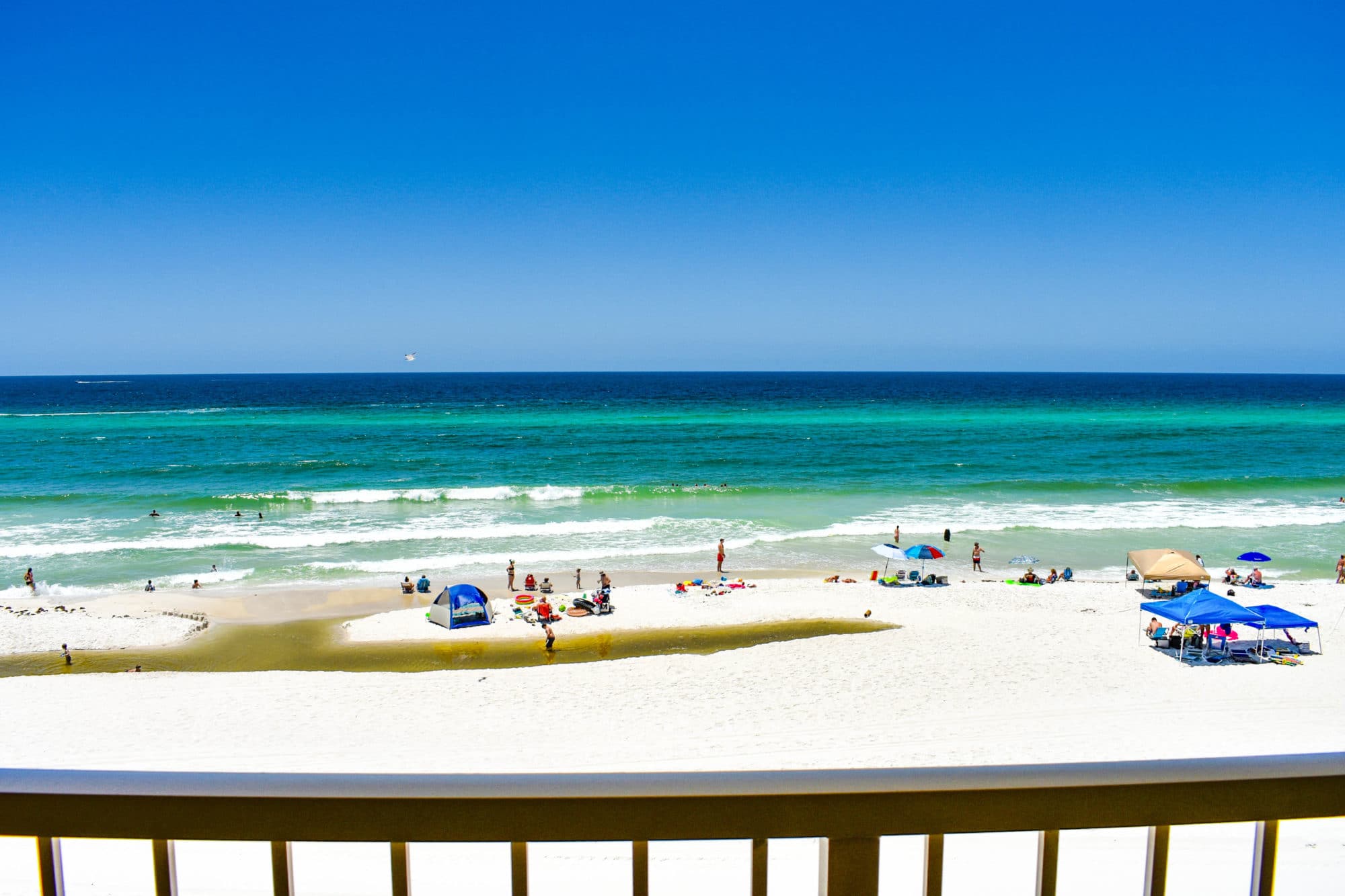 image From the balcony, beachgoers can be spotted enjoying the lively atmosphere below, with colorful umbrellas dotting the shoreline as gentle waves create a captivating backdrop to a perfect day by the ocean.