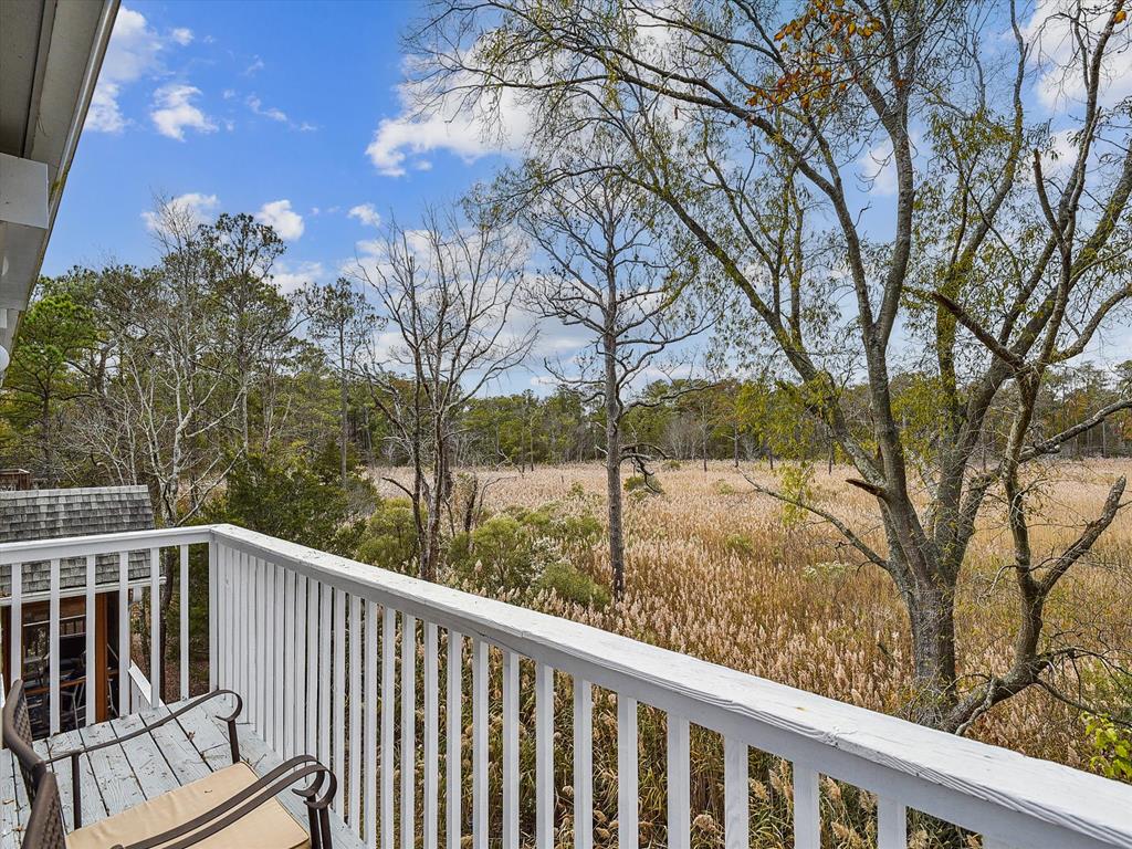 image Relax on the upper balcony and take in the picturesque views of the wetlands, framed by trees, offering a peaceful retreat to enjoy nature's beauty.