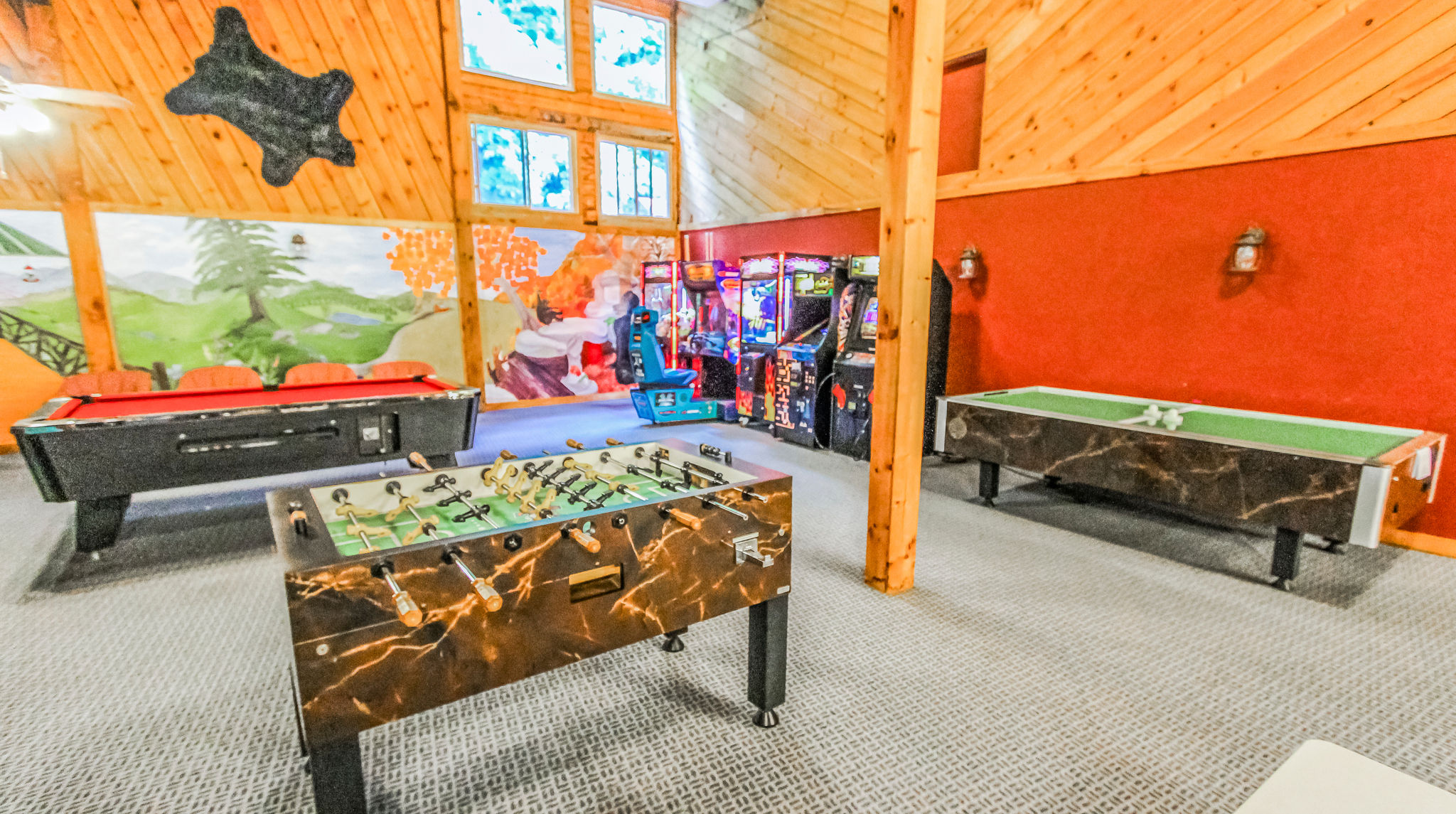 image The game room is filled with entertainment options, including a pool table, foosball, and arcade machines, all set against a vibrant, colorful backdrop.