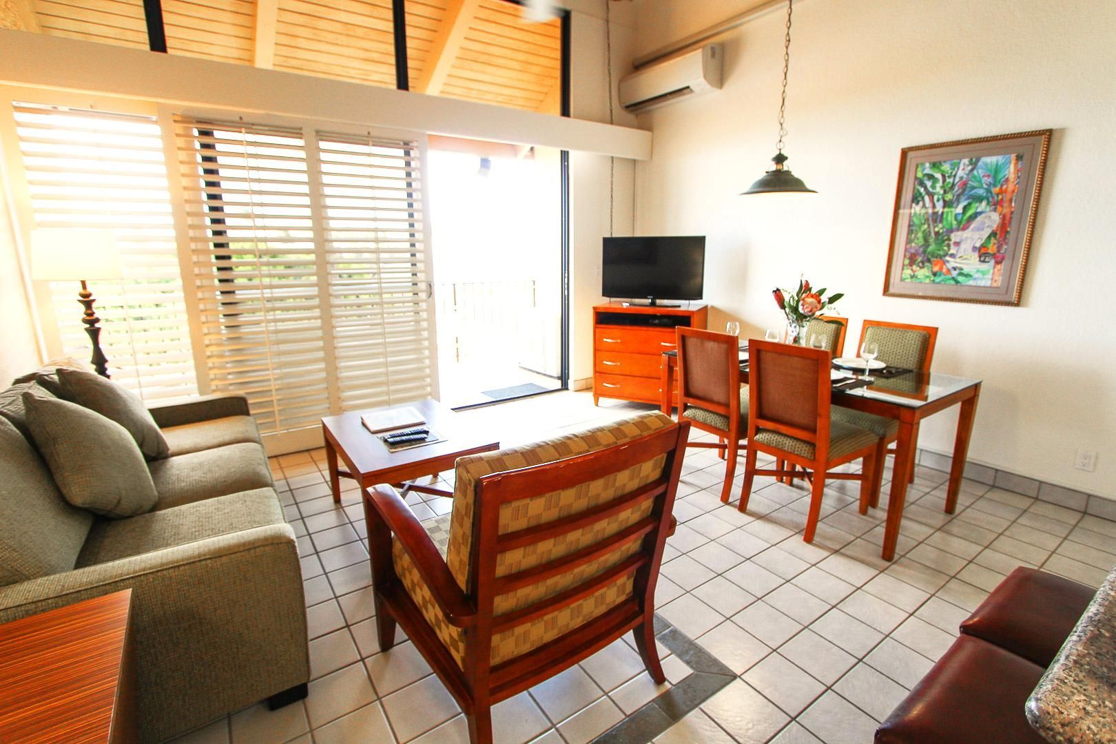 image An inviting interior space showcasing a living area with a comfortable sofa, a dining table, and large windows that allow natural light to fill the room, creating a warm and homey atmosphere.