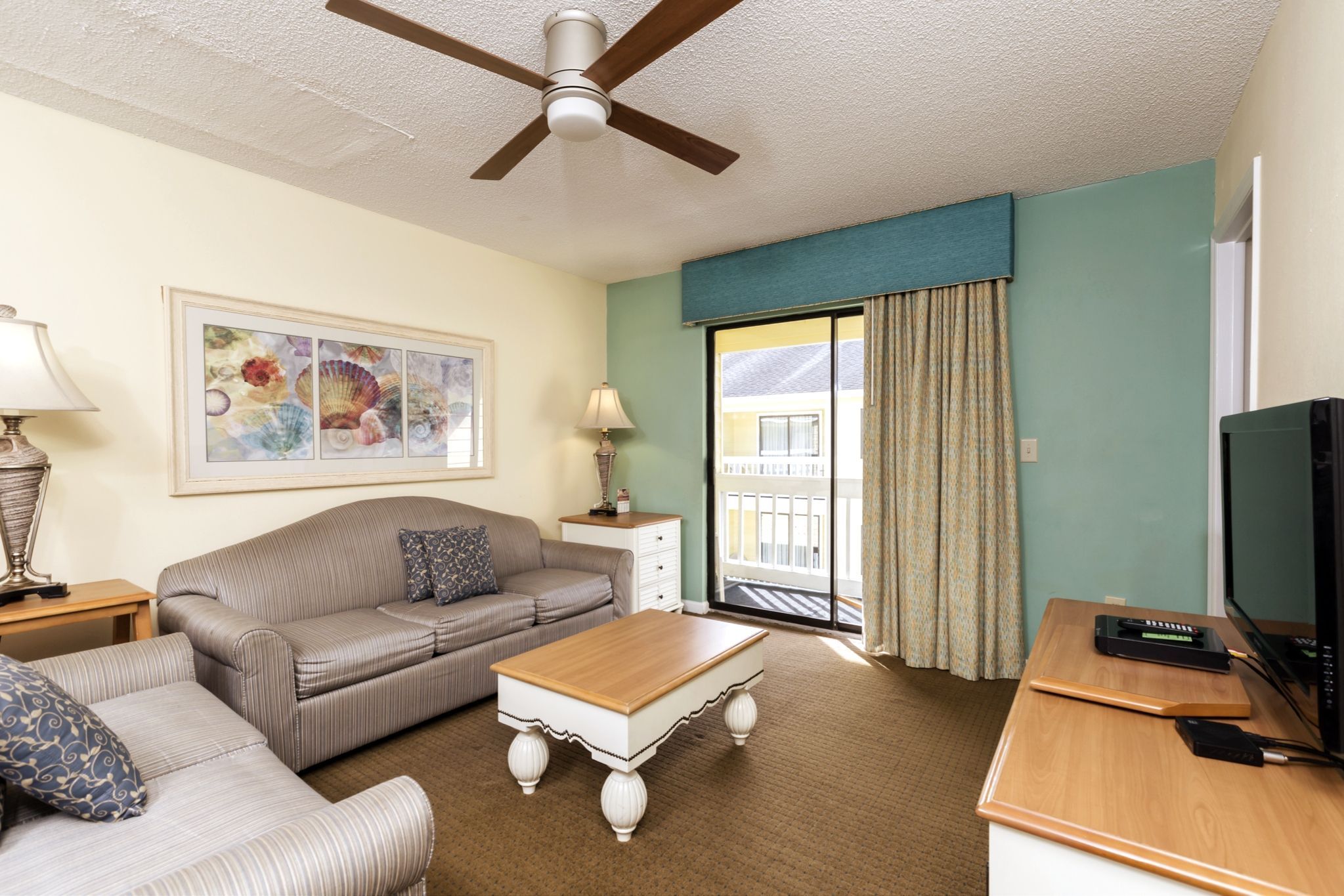 image Relax in the cozy living area of this 1-bedroom condo, featuring a comfortable sofa bed and easy access to a private balcony for stunning views.
