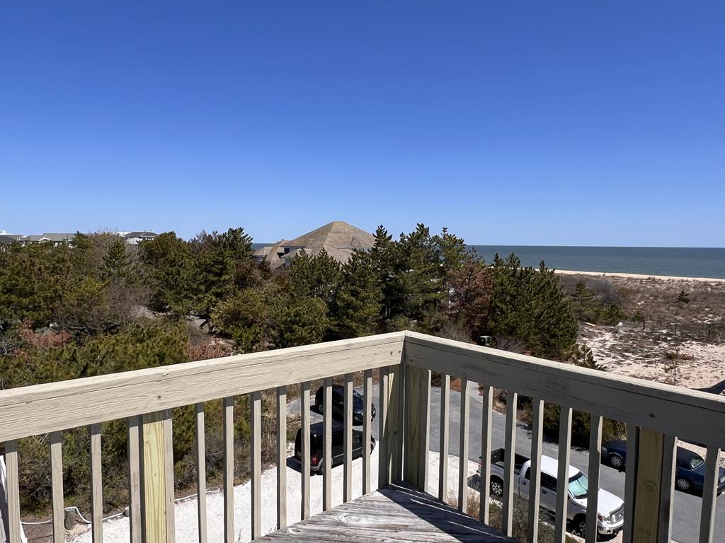 image From the deck, enjoy stunning views of the sandy beach and sparkling ocean, surrounded by lush greenery.