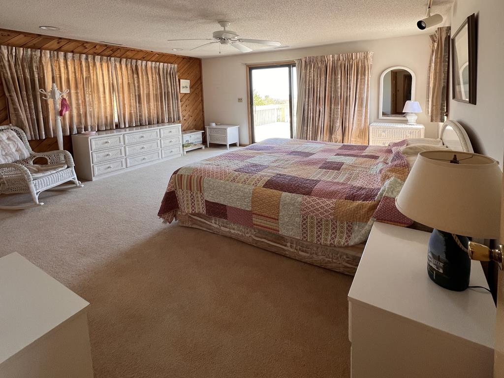 image The spacious master bedroom features a cozy quilted bed, natural light pouring in through large windows, and charming coastal decor.