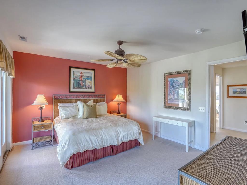 image This cozy second bedroom showcases a comfortable king-sized bed with decorative pillows, tasteful artwork, and ample natural light streaming through sliding doors that lead to a private deck.