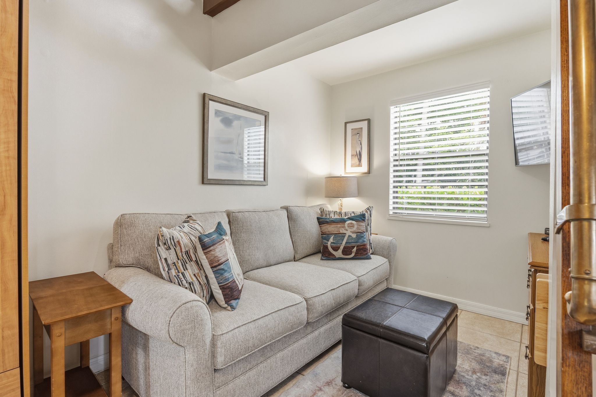 image A close-up view highlights the cozy sofa with decorative pillows and soft lighting in the studio living space.