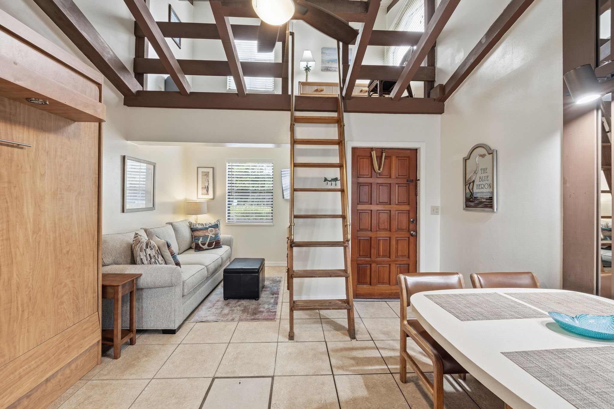 image The studio living area offers a comfortable sofa, wood accents, and a lofted sleeping space accessed by a ladder.