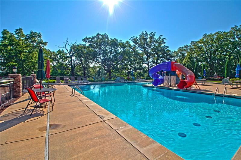 image Enjoy a sunny day splashing around in this expansive pool, complete with playful waterslides and scenic views of the surrounding nature.