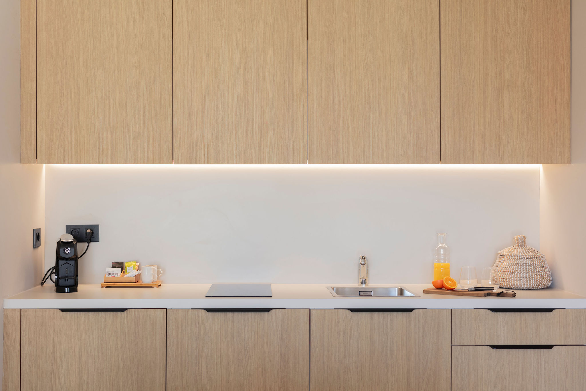 image Sleek kitchenette with modern cabinetry, ceramic hob, and coffee essentials—fully equipped for your convenience.