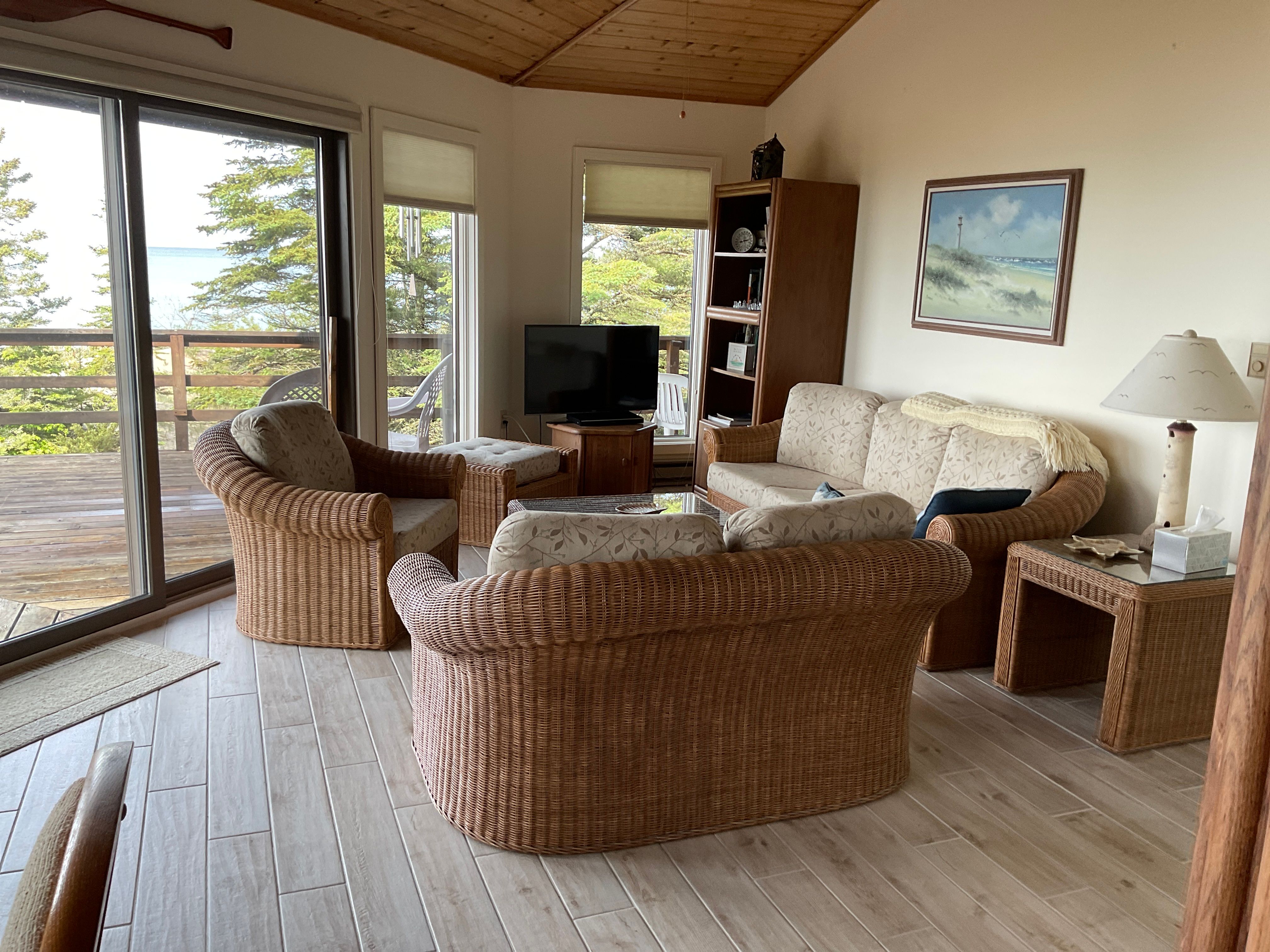 image Cozy living space with wicker furniture, lake-facing views, and direct access to the spacious wraparound deck.