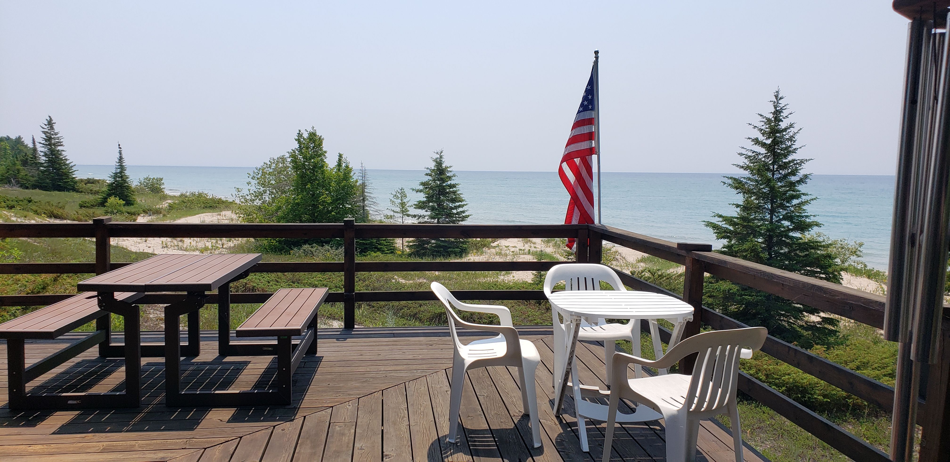 image Expansive deck with picnic seating and lounge chairs, ideal for outdoor dining or soaking in Lake Michigan views.