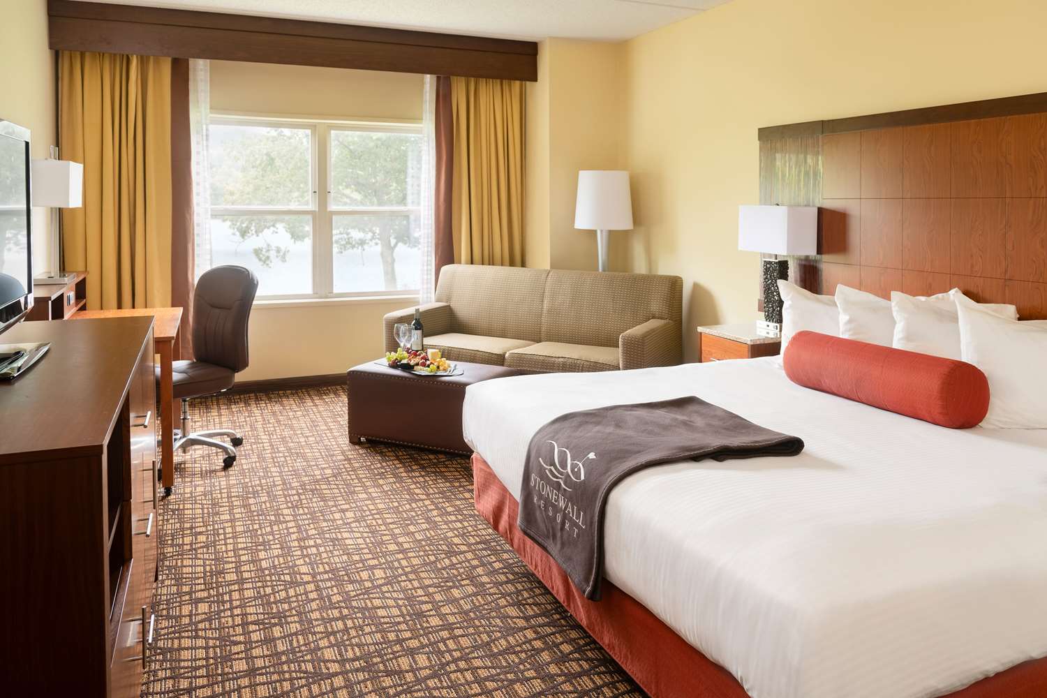 image Plush bedding, warm tones, and natural light come together in a cozy retreat with serene park views.