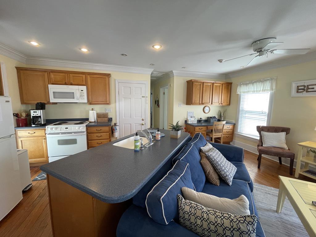 image The modern kitchen boasts sleek appliances nestled within honey-colored cabinetry, a spacious island perfect for gathering, and a sunlit open layout that seamlessly connects the cooking area to the inviting living space.