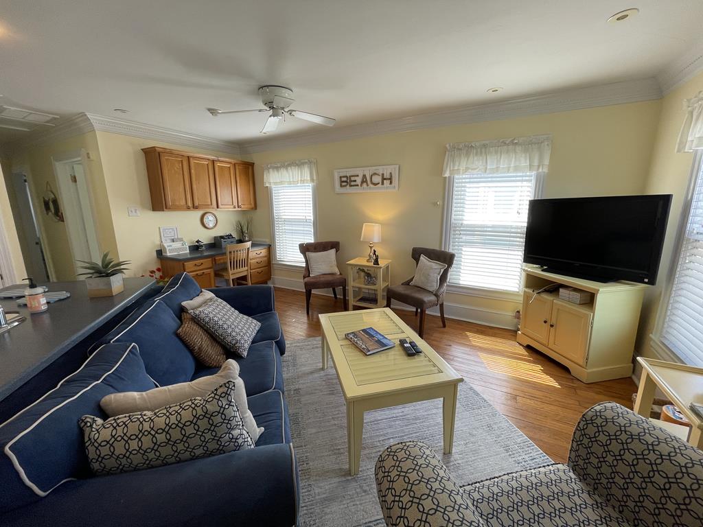 image The inviting living area features a cozy blue sofa adorned with decorative pillows, a warm wooden coffee table, and large windows that invite natural light, all framed by soft cream-colored walls, enhancing the relaxing beach vibe.