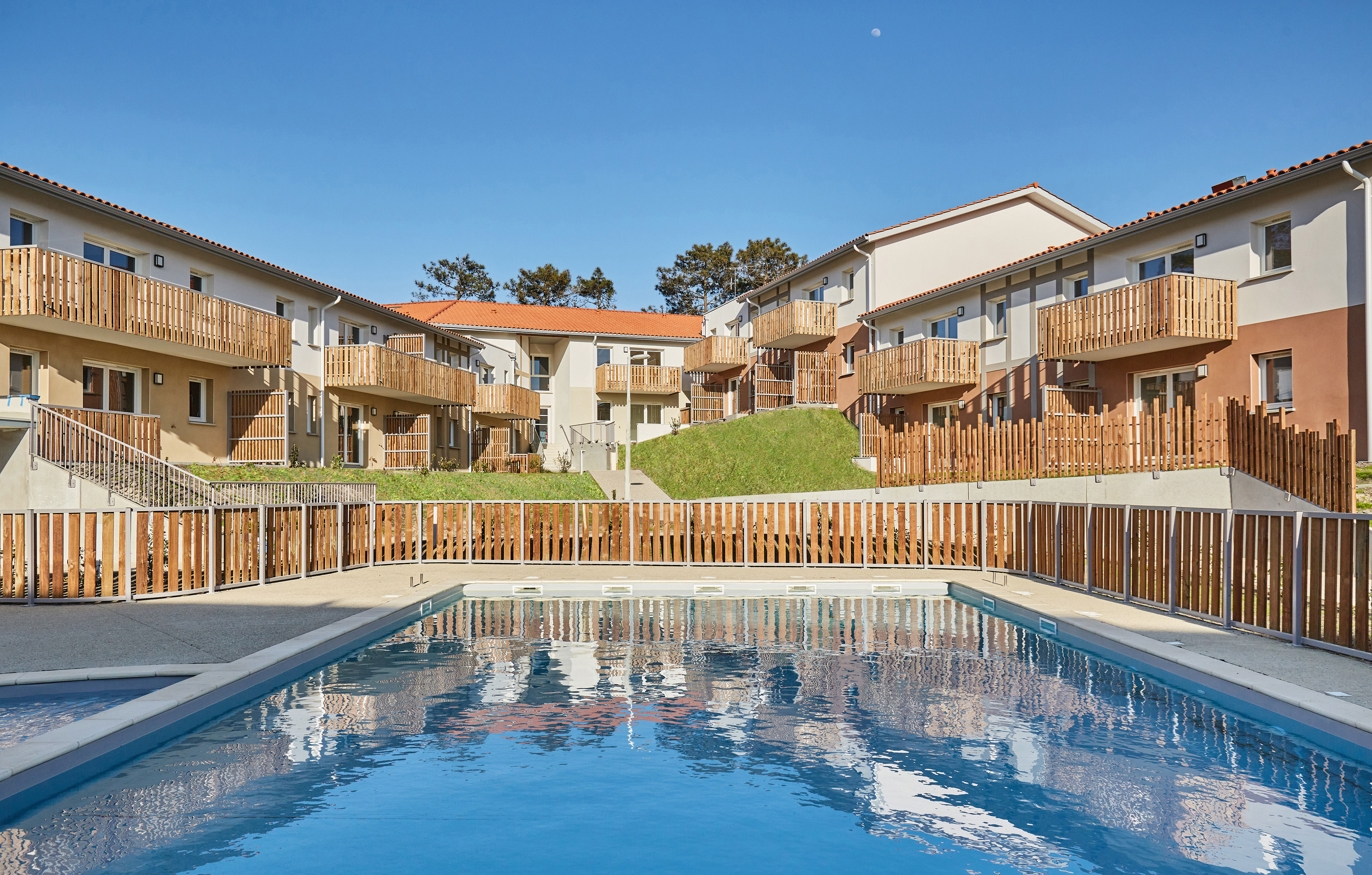 image Dive into relaxation at the shared heated pool, nestled amid charming architecture and lush greenery, inviting you to unwind after a day at the beach.
