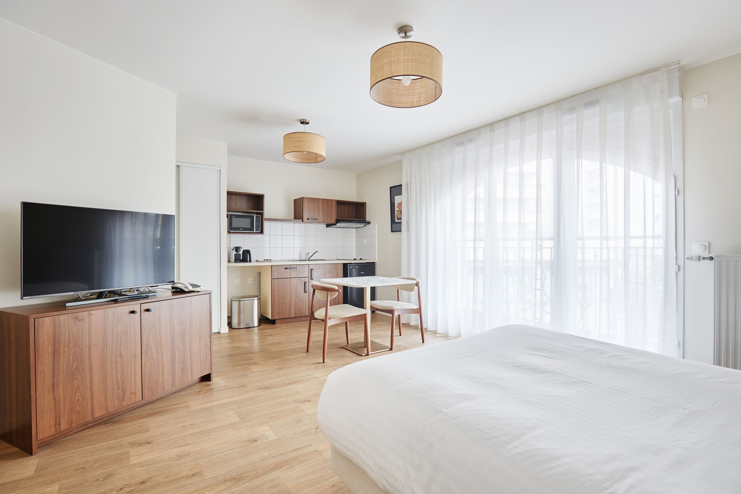 image Bright studio with a cozy double bed and flat-screen TV—perfect for couples or solo travelers seeking Parisian comfort.