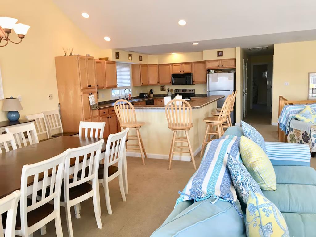 image The spacious open-concept living and dining area features a large table for group gatherings, alongside a well-equipped kitchen that boasts bar seating.