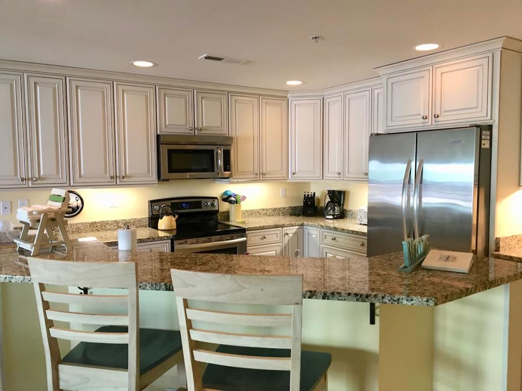 image Step into this gorgeous beach-area condo's kitchen, featuring modern appliances, elegant cabinetry, and a spacious layout perfect for family meals.