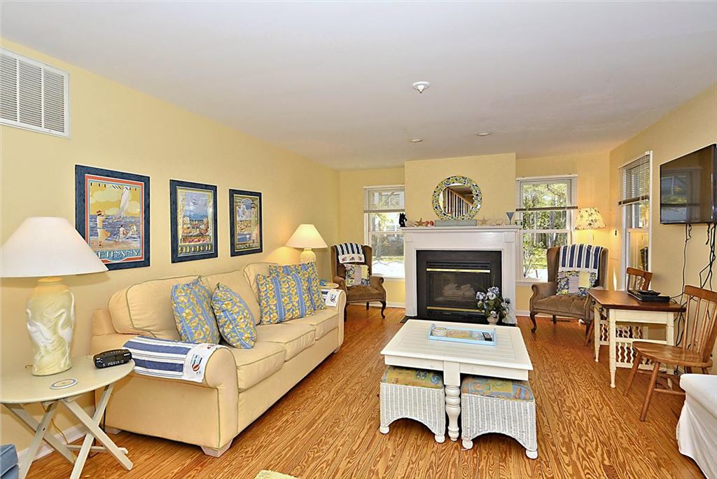 image The comfortable living room showcases a stylish sofa, decorative art pieces, and a fireplace, all amidst large windows that let in plenty of natural light.