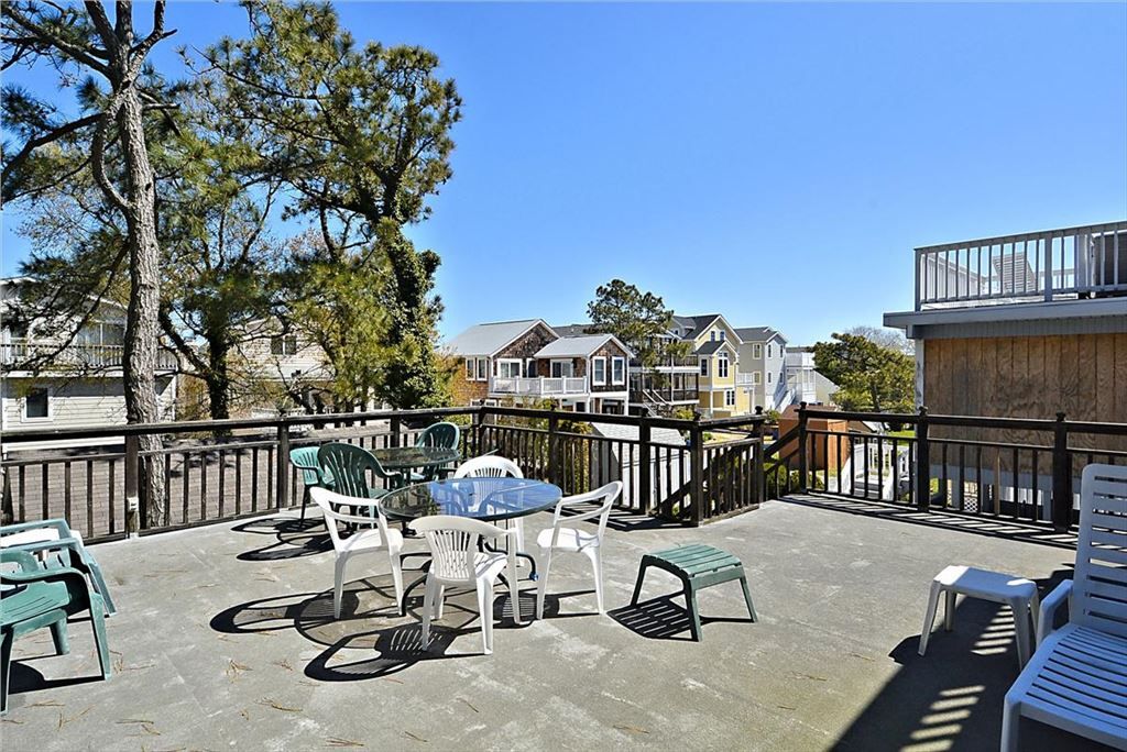 image A spacious rooftop deck is equipped with a dining table and several chairs, surrounded by trees, perfect for enjoying the fresh air.